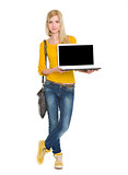 Full length portrait of happy student girl showing laptop