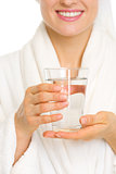Closeup on smiling young woman in bathrobe with glass of water