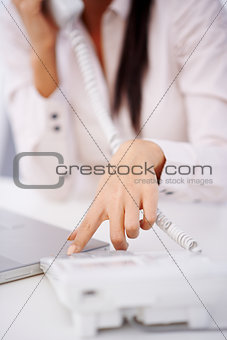 Close up of a woman dialing on telephone