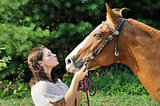 Young adult woman kissing her horse
