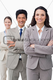 Smiling businesswoman with team and folded arms