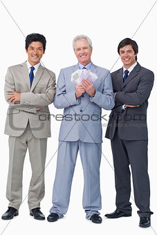 Smiling senior salesman with money and employees