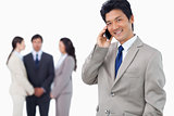 Smiling businessman on cellphone and team behind him
