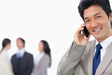 Smiling businessman on mobile phone and team behind him