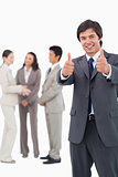 Salesman giving thumbs up with team behind him