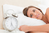 Woman looking agitated by her alarm clock