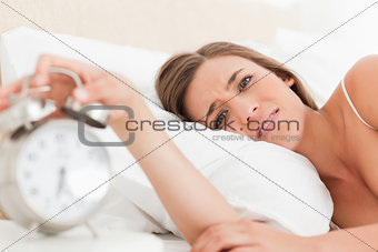 Woman looking forward as she silences her alarm clock