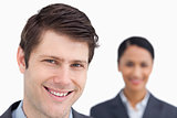 Close up of smiling salesman with colleague behind him