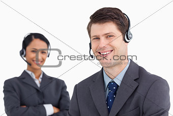 Close up of smiling male call center agent with colleague behind