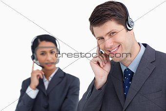 Close up of smiling call center agent with co-worker behind him
