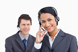 Close up of smiling call center agent with colleague behind her