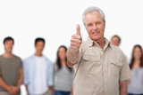 Thumb up given by mature man with young people behind him