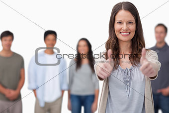Smiling woman with friends behind her giving thumbs up