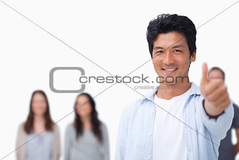 Smiling male with friends behind him giving thumb up