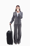 Businesswoman with a suitcase drinking a coffee