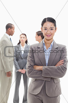 Businesswoman smiling and crossing her arms with co-workers