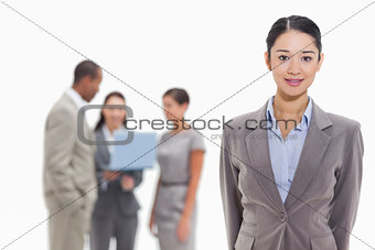Businesswoman with co-workers watching a laptop in the backgroun