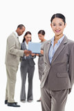 Businesswoman smiling with co-workers watching a laptop in the b