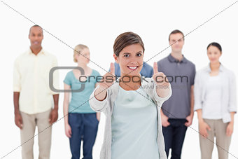 Close-up of a woman smiling giving the thumbs-up with people beh
