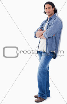 Man crossing his arms and leaning against a wall
