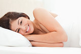 A woman lying on a bed, with her eyes open and smiling 