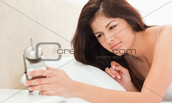 Woman lying on a bed, holding a clock in hand and looking at the
