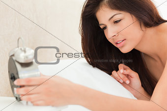 Woman holding a clock in her hand and looking at the time