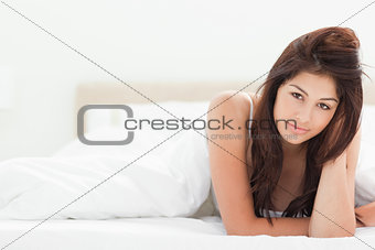 A woman at the end of the bed under the quilt One arm by her hai