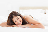 Woman lying on the bed, looking forward and smiling with her hea