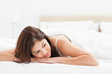 Woman lying at the end of the bed with her head looking to the s