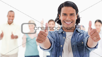 Close-up of a man with his thumbs-up with people behind