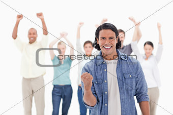 Close-up of a man clenching his hand with people raising their a