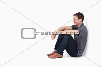 Smiling man sitting against a wall 