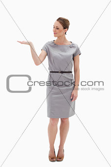 Woman in a dress presenting something with her hand