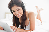 Woman using a tablet and headphones while looking up and smiling