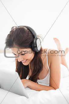 Close up, woman on the bed using a tablet and headphones with he