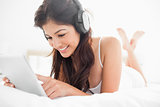 Woman using a tablet and headphones with her legs crossed