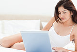 Woman lying on her bed in front of her laptop and browsing as sh