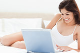 Woman on her laptop smiling as she watches her programme while s