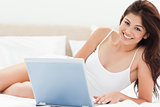 Woman looking forward and smiling as she uses her laptop on the 
