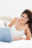 Close up, woman lying on her bed, looking forward and smiling wi