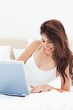 Close up, woman using her laptop and smiling while lying on the 