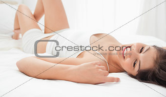 Woman relaxing on her bed on her back, smiling with a knee raise