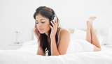 Woman holding her headphones while listening to music with her e