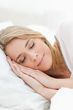 Close up, woman asleep with hands beside her head resting on a p