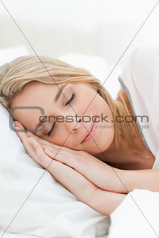 Close up, woman asleep with hands beside her head resting on a p