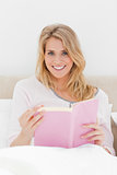 Close up shot, Woman sitting in bed, book in hand as she looks f