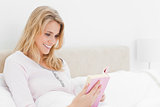 Side angle shot, Woman in bed, reading her book while smiling