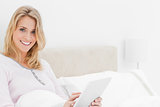 Closer shot, Woman in bed with tablet pc in hand, looking up and