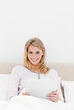 Centered shot, Woman sitting in bed with a tablet pc, looking ah